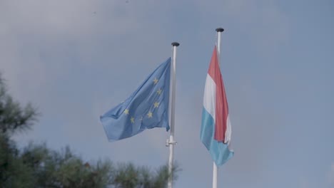 Die-Flaggen-Der-Europäischen-Union-Und-Luxemburgs-Wehen-Vor-Einem-Blauen-Himmel-Mit-Wolken