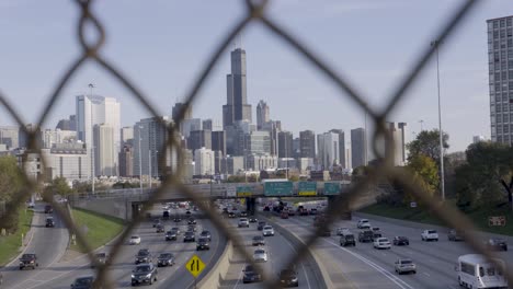View-of-Chicago's-skyline-and-busy-expressway-through-chain-link-fence