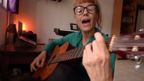 Home-Serenade:-Attractive-Woman-wearing-glasses-is-Playing-Guitar-and-Singing