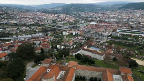 Aerial-dolly-over-orange-roof-of-Catholic-seminary-religious-school-to-stunning-Ourense-city-panoramic-views