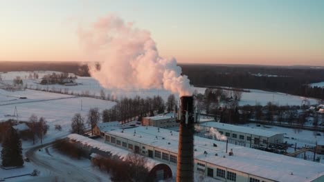Aerial-view-during-sunset-golden-hour-of-high-chimney-release-smoke-in-air