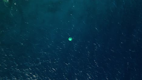 Aerial-drone-top-down-of-buoy-in-open-green-blue-gradient-ocean-water