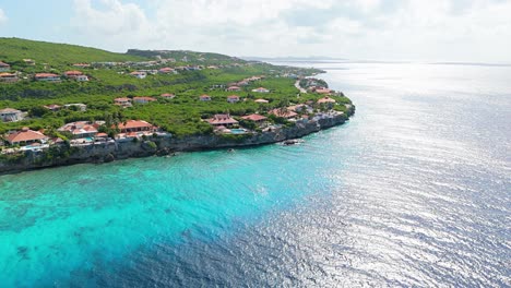 Panoramic-aerial-orbit-of-stunning-cliffside-villas-looking-out-over-crystal-clear-water-and-coral-reef