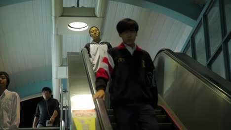 Young-asian-adults-walking-quickly-down-escalator-stairs-in-Taiwan-metro-station
