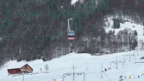 Seilbahnen-Fahren-Die-Verschneiten-Berghänge-Hinunter,-Während-Touristen-Unten-An-Einem-Berghang-In-Engelberg-In-Brunni,-Schweiz,-Ski-Fahren