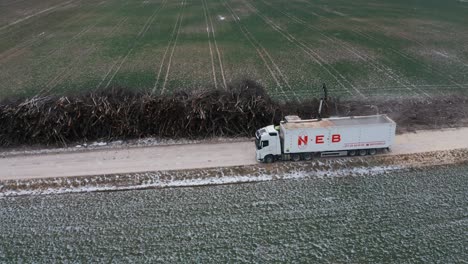 Aerial-view-of-wood-chipper-shred-tree-branches-from-pile-into-truck-trailer