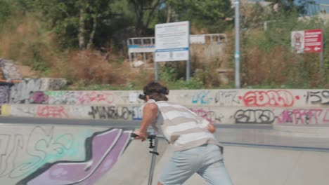 Professional-stunt-scooter-rider-ride-on-skatepark-graffiti-covered-bowl