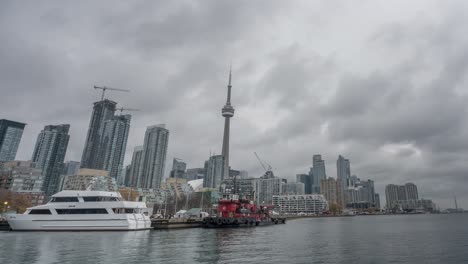 Zeitrafferaufnahme-Der-Skyline-Von-Toronto-Mit-Parkender-Yacht-Am-Pier-Und-CN-Tower-Im-Hintergrund-An-Einem-Bewölkten-Tag-–-Totalaufnahme