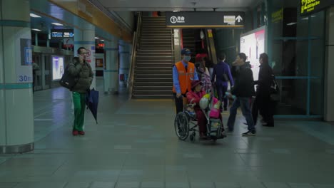 Walking-Asian-commutors-and-disabled-person-in-wheelchair-changing-plattform