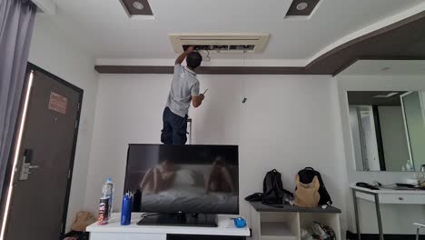 Man-repairing-the-air-conditioning-system-in-a-hotel-room