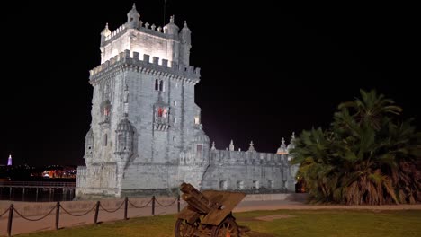 Iconic-Belém-Tower-from-the-surrounding-park-at-night-with-a-historical-cannon-in-the-foreground-in-Lisbon,-Portugal