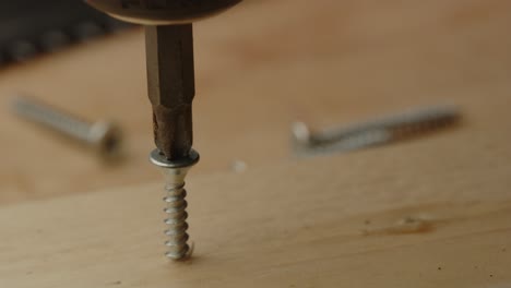Macro-view-of-electric-screwdriver-drilling-screw-in-wooden-board-on-a-construction-site-in-slow-motion