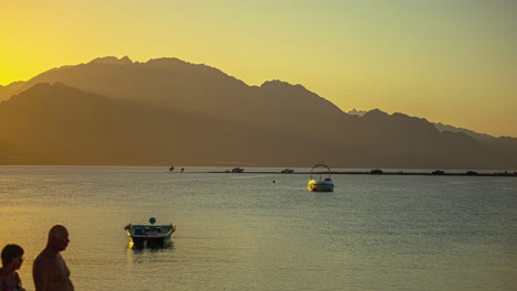 Silhouette-of-mountain-and-moored-motor-boats-during-sunset,-time-lapse