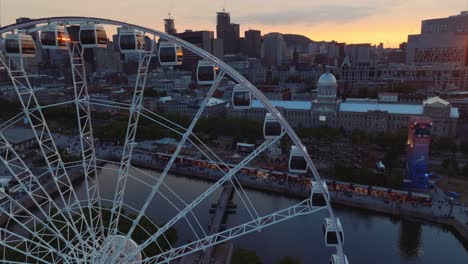 Drone-backing-reveals-wide-sunset-view-of-Old-Montreal-skyline-at-sunset-and-La-Grande-Roue
