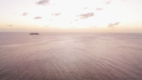 High-angle-aerial-of-golden-hour-sky-light-on-ocean-ripples-with-silhouette-of-cruise-ship
