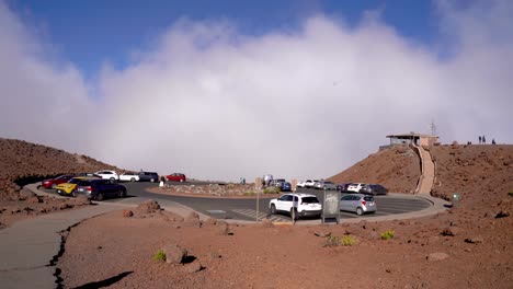 Parking-lot-and-visitor-center-seen-at-the-top-of-Haleakala-National-Park-in-Maui,-Hawaii,-Haleakala-visitor-center-pictured-above-the-clouds-before-sunset
