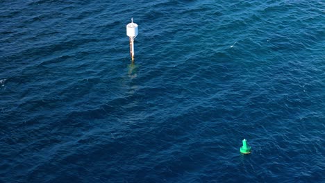 Aerial-orbit-around-large-green-and-white-tall-buoy-markers-for-maritime-navigation