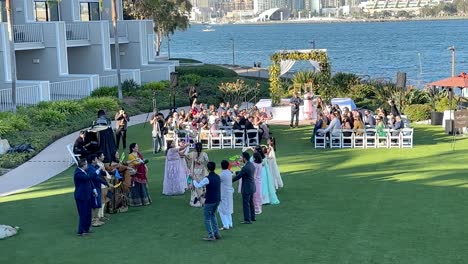 Bride-makes-her-grand-entrance-at-a-traditional-Indian-wedding-ceremony-on-a-lawn-of-a-waterfront-hotel