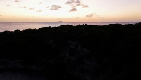 Aerial-dolly-ascend-to-reveal-cruise-ship-sailing-across-open-Caribbean-sea-at-sunset