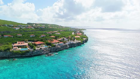 Drone-approaches-luxury-villas-looking-out-on-crystal-clear-Caribbean-ocean-water