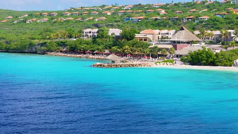 Atemberaubendes-Blaues-Karibisches-Wasser-Mit-Cabanna-Villen-An-Der-Küste-Einer-Tropischen-Insel