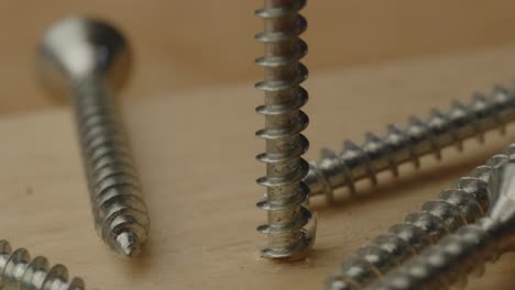 Macro-view-of-rotating-screw-falling-out-of-wooden-beam-in-slow-motion