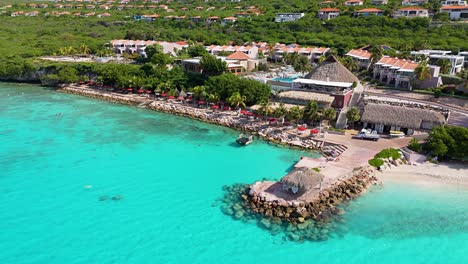 Drone-right-to-left-orbit-around-clear-Caribbean-waters-splashing-against-Karakter-beach's-white-sand