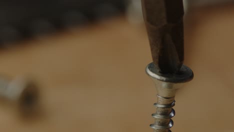 Macro-view-of-drill-bit-trying-to-screw-in-slanted-screw-with-electric-screwdriver