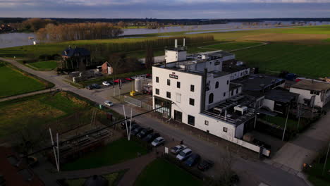 Drone-moves-backwards-in-front-of-industrial-factory-facade-next-to-Meuse-river