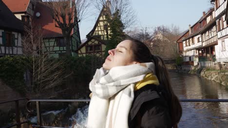 Touristin-Genießt-Das-Sonnenlicht,-Das-Ihr-Gesicht-An-Einem-Kalten-Wintertag-In-Der-Touristischen-Mittelalterlichen-Stadt-Kaysersberg-Trifft