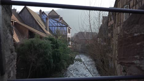 Scenic-wide-shot-of-half-timbered-houses-near-the-Weiss-river-stream-flowing-through-medieval-town-in-France,-Kaysersberg