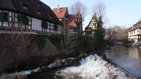 Wide-shot-of-the-Weiss-river-streaming-through-medieval-village-of-kaysersberg,-with-half-timbered-architectural-buildings,-France