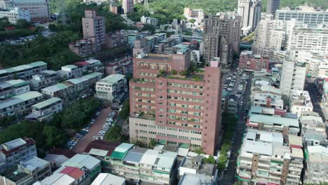 Aerial-drone-rotating-shot-over-Taipei-Guandu-Hospital-building-with-parking-lot-on-both-sides-in-Beitou-District,-Taipei,-Taiwan-at-daytime