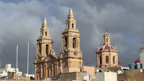 Iglesia-Parroquial-De-Nuestra-Señora-Del-Sagrado-Corazón,-Sliema,-Malta:-Toma-De-4k-Que-Muestra-La-Arquitectura-Neogótica-Contra-Nubes-Dramáticas