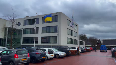 Ein-Blauer-Lieferwagen-Fährt-An-Der-Ukrainischen-Flagge-Vor-Dem-Rathaus-Von-Nieuw-Bergen-In-Limburg-Vorbei