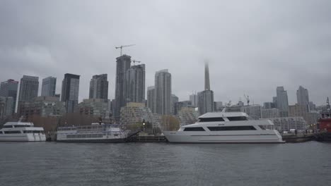 Zoom-out-shot-of-parking-ship-and-yacht-at-Waterfront-of-Toronto-city-with-skyline-in-background---Wide-shot