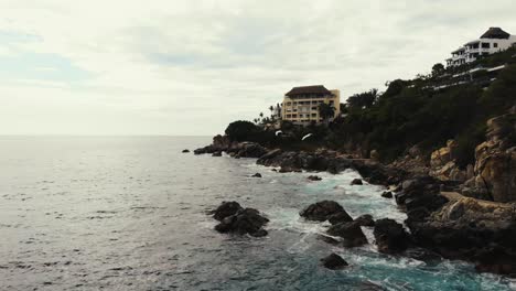 Puerto-Escondido's-rocky-coastline-with-villas-and-flying-seagulls