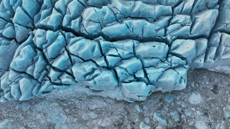Aerial-top-view-of-textured-ice-formations-of-a-glacier-in-Iceland,-at-dusk