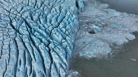 Aerial-view-over-textured-ice-formations-of-a-melting-glacier-in-Iceland,-at-dusk