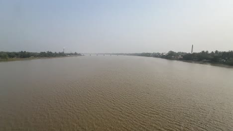 Ultra-wide-cinematic-shot-of-a-river-in-between-a-land-with-industries-during-daytime-in-Bengal,-India