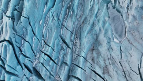 Aerial-top-view-over-textured-ice-formations-of-a-glacier-in-Iceland,-at-dusk