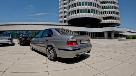 Silver-BMW-M5-E39-Car-parked-outside-museum-in-Munich,-Germany-with-people-walking-around-it