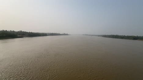 Wide-angle-shot-of-a-muddy-river-Hoogly-flowing-during-sunset-in-Bengal,-India
