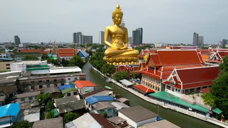 Golden-Buddha-Statue-Wat-Paknam-Bhasicharoen-in-Phasi-Charoen-District-in-Bangkok-Near-Chao-Phraya-River-Cruise-Thailand---aerial-pull-back