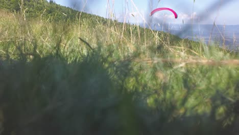 Paraglider-flying-left-to-right-toward-valley-below