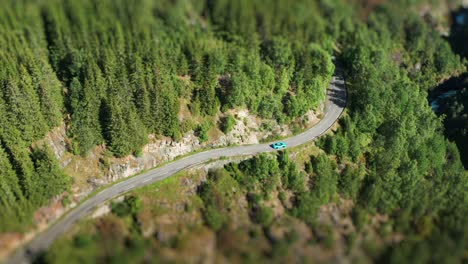 A-turquoise-colored-car-follows-the-narrow-Aurlandsvegen-tourist-road-through-the-summer-landscape