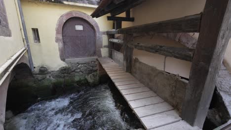 Frontal-door-towards-traditional-half-timbered-house-with-wooden-bridge-to-cross-the-river-stream