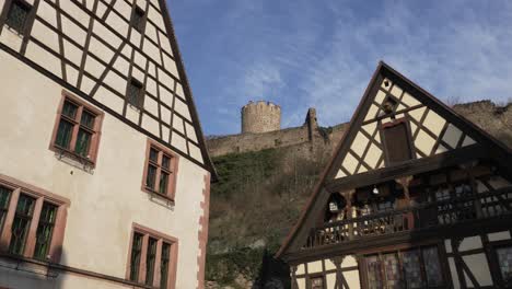 Sunlight-hitting-beautiful-half-timbered-architectural-houses,-in-the-background-the-scenic-castle-overviewing-Kaysersberg