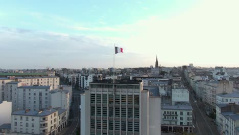 Majestic-aerial-rise-ascending-waving-French-flag-in-City-Brest