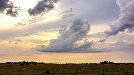 Stürmische-Wolken-Ziehen-über-Landwirtschaftliche-Felder,-Nachdem-Weizenkörner-In-Stapeln-Geerntet-Wurden